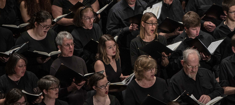 Men and woman holding folders singing