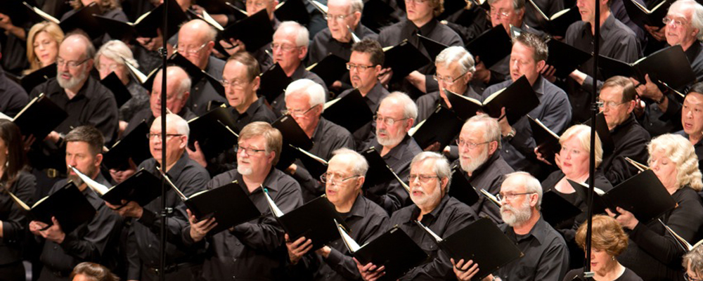 Chorus with men and women holding sheet music singing
