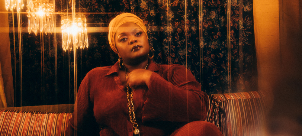 Kyshona sitting on couch with chandelier above